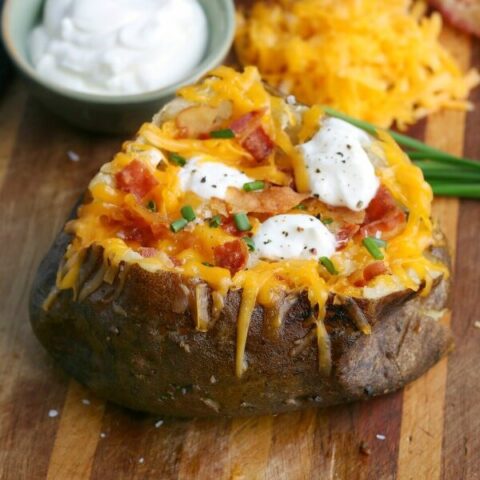 finished baked potato wopped with cheese, sour cream, bacon, and chives