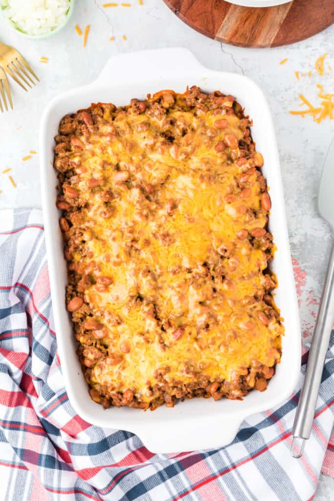 Baked Chili Dog Casserole topped with melted Cheddar cheese in a white baking dish.