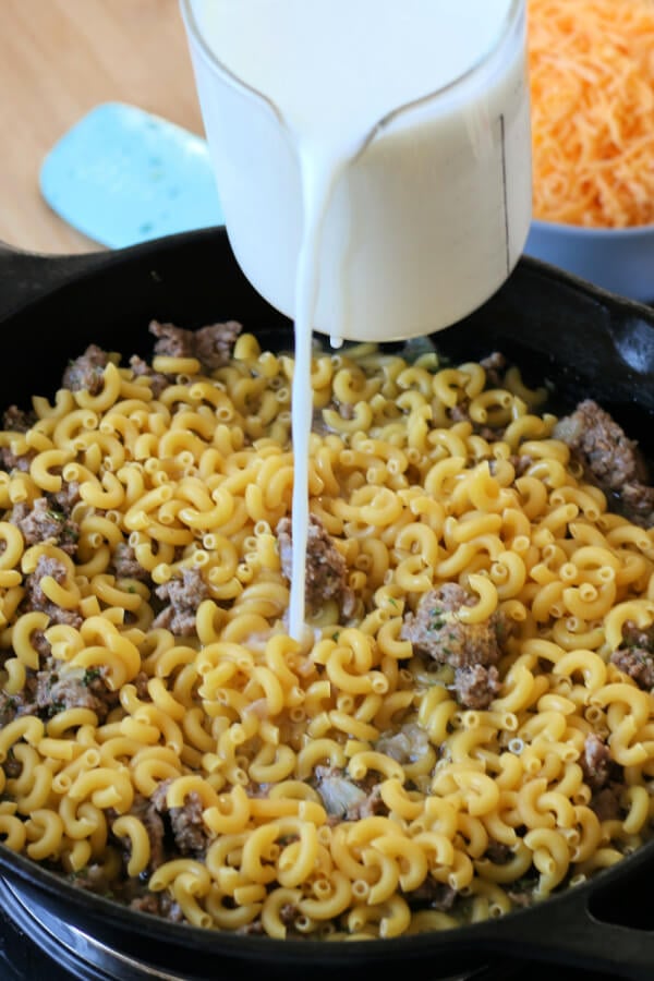 adding noodles and milk to the skillet
