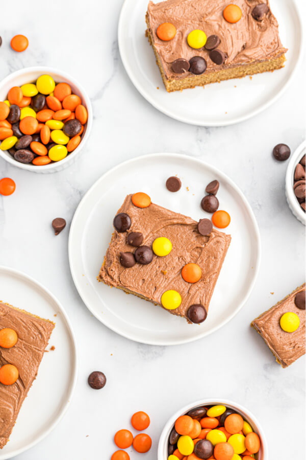 looking down onto white plates with cookie bars and candies