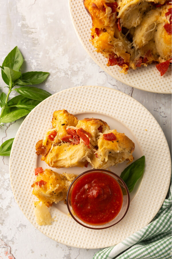 pieces of monkey bread on plate with pizza sauce