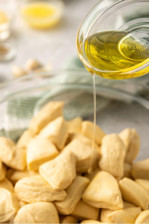 oil being poured over the biscuits in a bowl