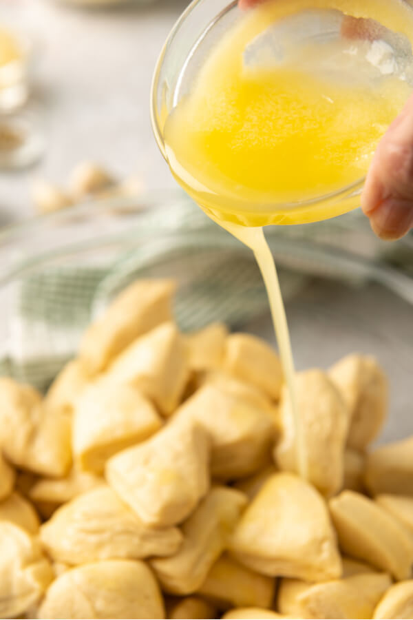 pouring melted butter into the bowl with the biscuits