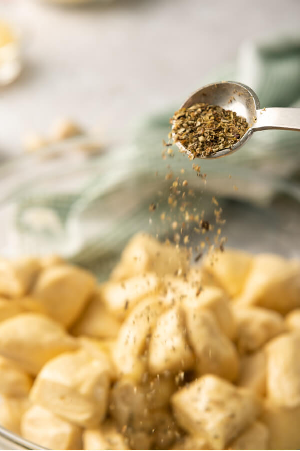 adding spices to the bowl of cut up biscuits