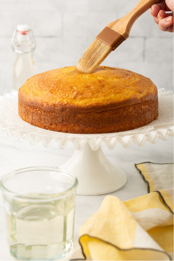 simple syrup being brushed onto baked cake layer