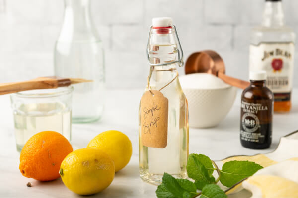 simple syrup in jar with orange, lemon, vanilla, mint, and sugar near by