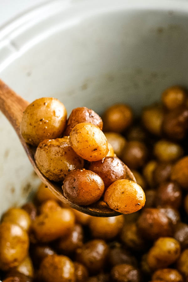 cooked potatoes on wooden spoon over slow cooker crock