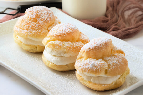 three finished cream puff on white rectangle plate