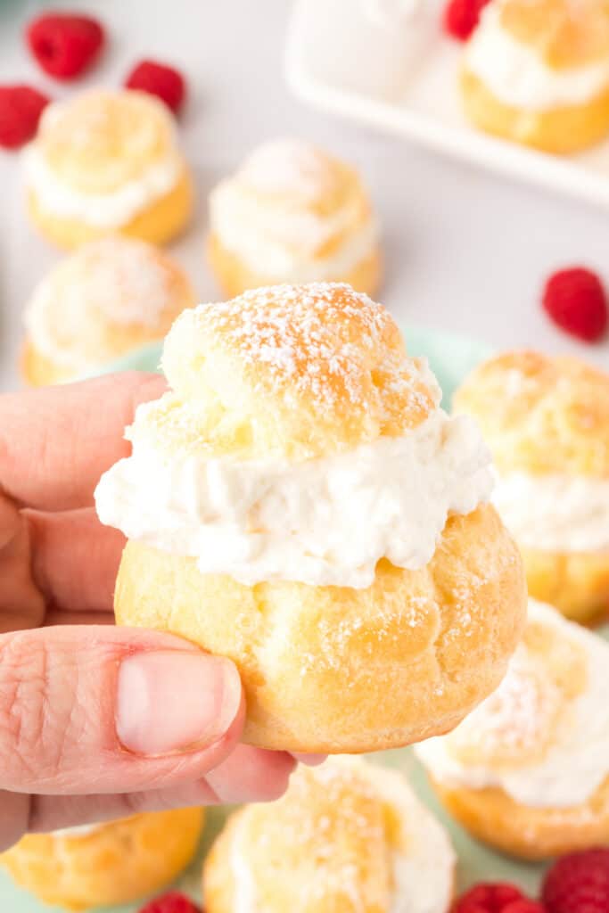 hand holding a cream puff dessert