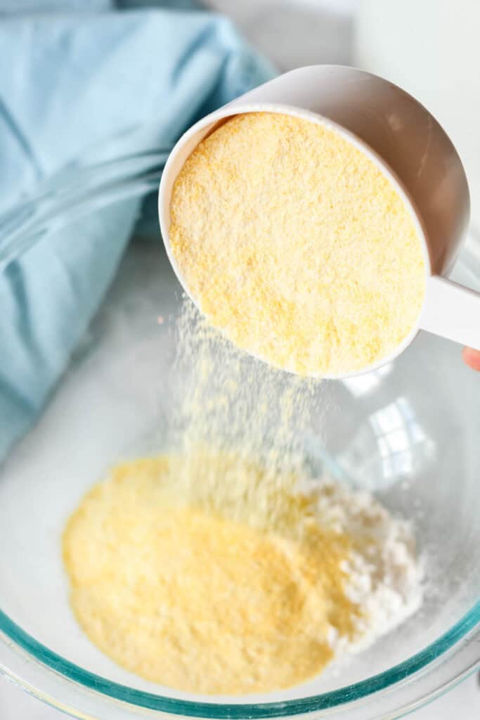 Yellow cornmeal being added to a bowl of flour for the fried fish coating