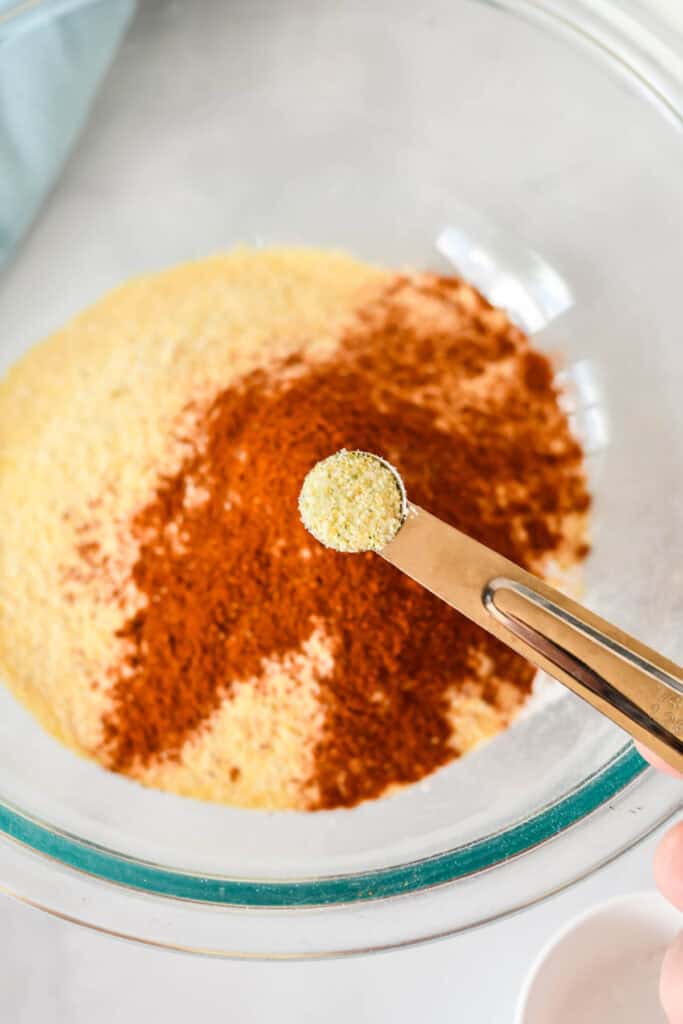Garlic powder being added to the seasoned cornmeal coating for fried fish
