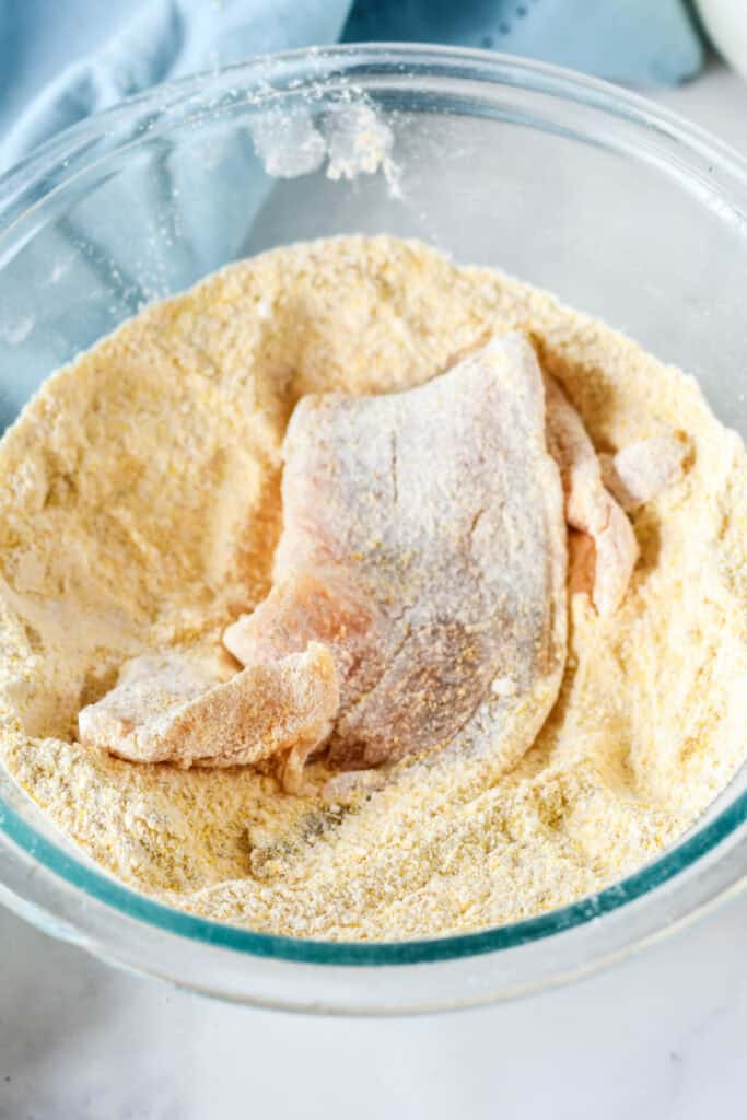 Fish fillets coated in seasoned cornmeal mixture before frying