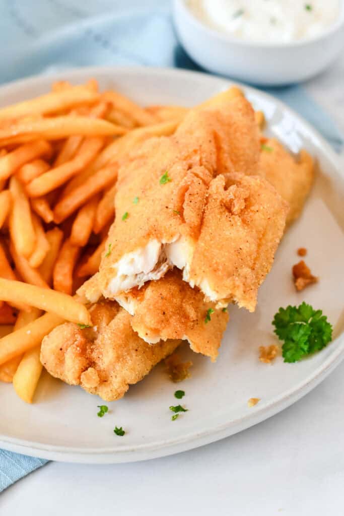 Crispy fried fish broken open to show the tender flaky white fish inside