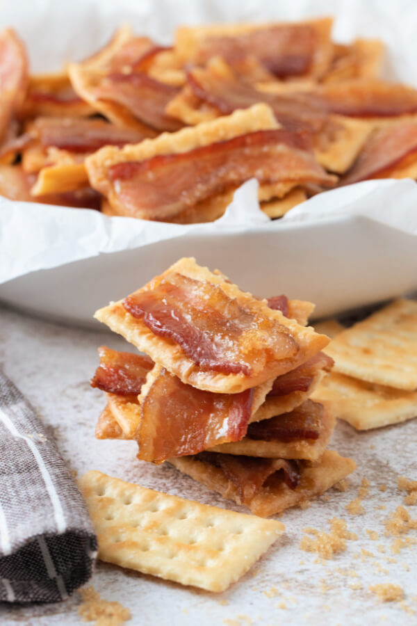 five bacon crackers stacked in front of a bowl with more crackers