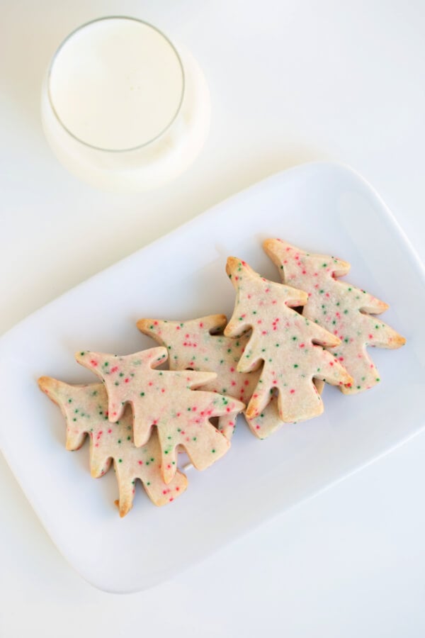 tree-shaped cookies on white plate with a glass of milk