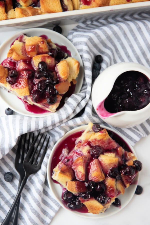 looking down onto two plates with food and a serving vessel with bluberry syrup