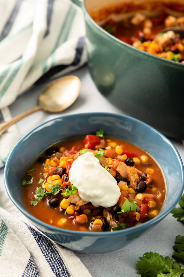 chipotle chicken soup in bowl with dollop of sour cream and sprinkle of cilantro