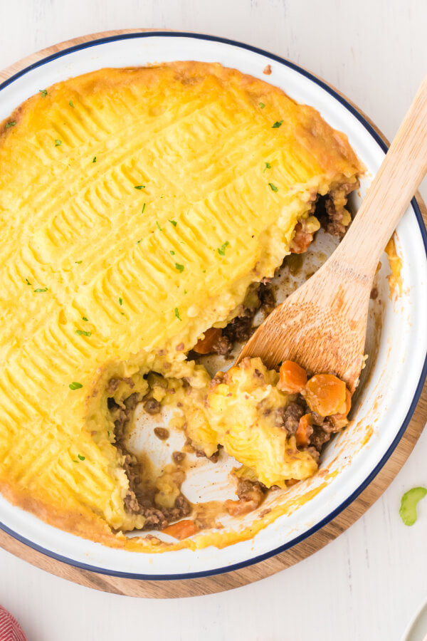 shepherds pie with wooden spoon scooping casserole