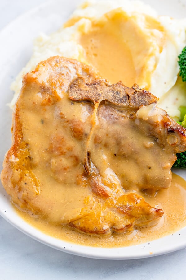 pork chop with gravy next to mashed potatoes with gravy