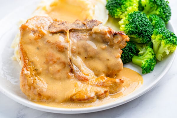 baked pork chop on plate with steamed broccoli