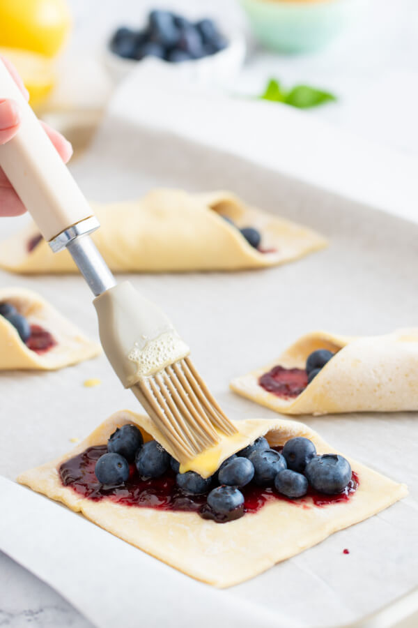 how to fold danish pastry - fold one corner over and brush it with egg wash