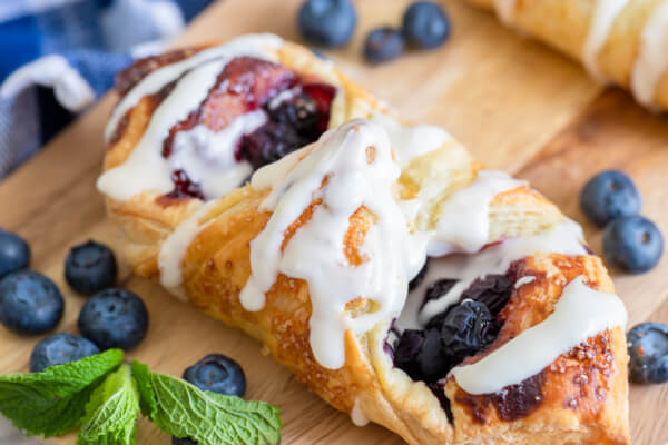 lemon blueberry danish on wooden cutting board with fresh blueberries