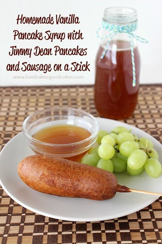 Homemade Vanilla Syrup with Jimmy Dean Pancakes & Sausage on a stick. A breakfast pancake and sausage on a plate with syrup and green grapes.