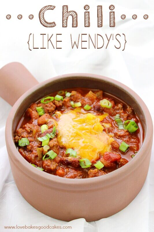 A bowl of chili with melted cheese and green onions.