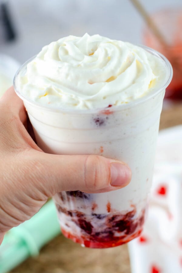 hand holding strawberries and cream frappuccino drink