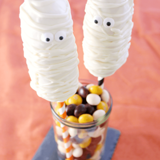 Mummy Twinkie Pops in a glass jar with jelly beans.