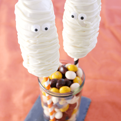 Mummy Twinkie Pops in a glass jar with jelly beans.