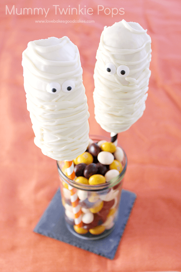 Mummy Twinkie Pops in a glass jar with jelly beans.