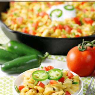 Fiesta Mac & Cheese on a white plate with a skillet and fresh vegetables.