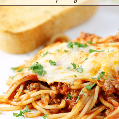 Cheesy Baked Spaghetti on a white plate with a slice of French bread.