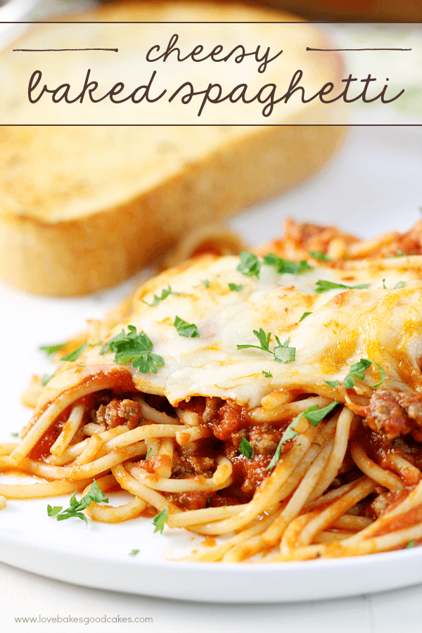 Cheesy Baked Spaghetti on a white plate with a slice of French bread.