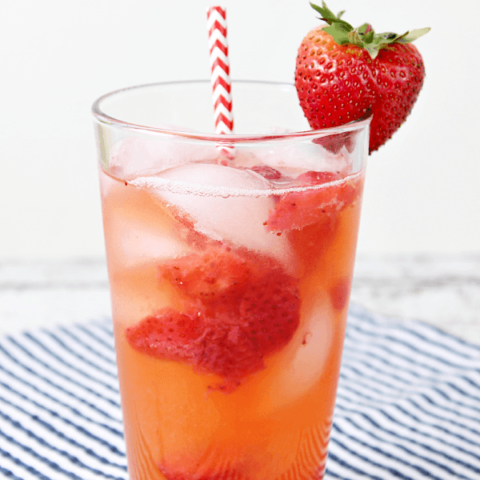 Copycat Red Robin Freckled Lemonade in a glass with a strawberry and a straw.