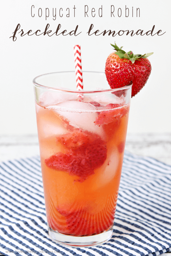 Copycat Red Robin Freckled Lemonade in a glass with a strawberry and a straw.