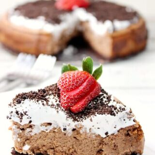 Oreo Chocolate Irish Cream Cheesecake with Irish Cream Whipped Cream close up on a white plate.