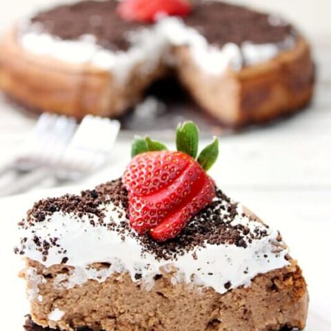 Oreo Chocolate Irish Cream Cheesecake with Irish Cream Whipped Cream close up on a white plate.