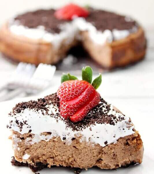 Oreo Chocolate Irish Cream Cheesecake with Irish Cream Whipped Cream close up on a white plate.