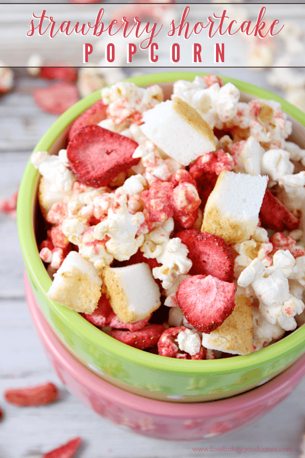 Strawberry Shortcake Popcorn in a green bowl with fresh strawberries.