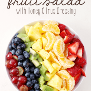Rainbow Fruit Salad with Honey Citrus Dressing in a white bowl.