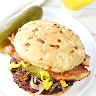 Rouladen Burger on a white plate with a pickle.