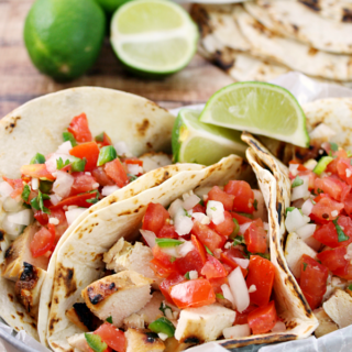 Grilled Chicken Fresco Tacos in a metal bowl lime slices.