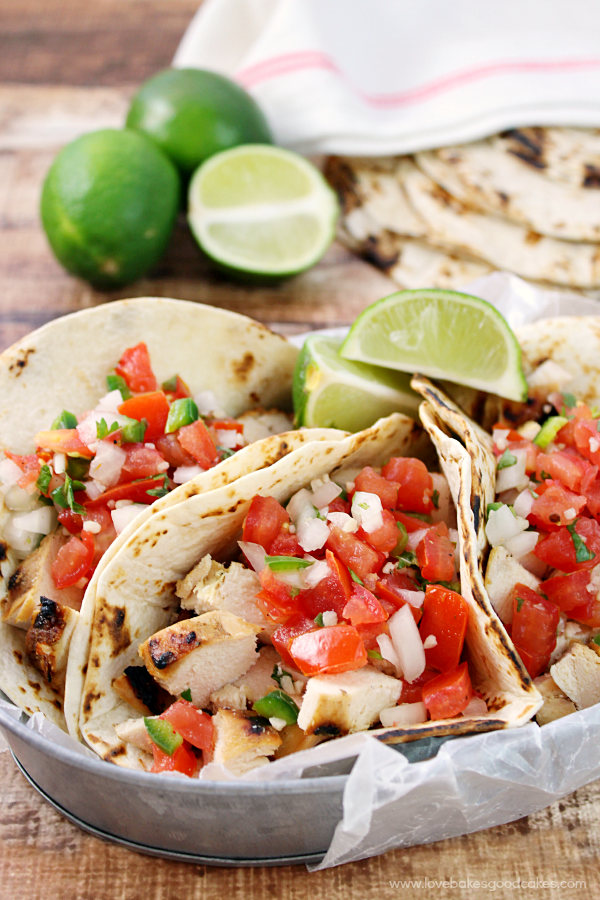 Grilled Chicken Fresco Tacos in a metal bowl lime slices.