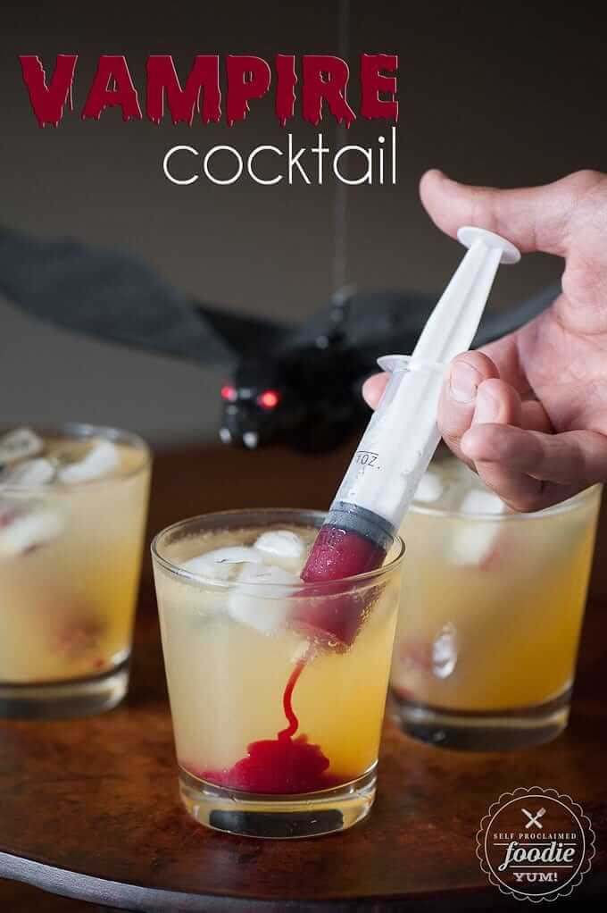 Vampire cocktail in a syringe being injected into a glass with a beverage.