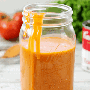 Tomato Soup Salad Dressing in a jar with the lid off and some dressing dripping down the side.