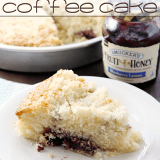 Blueberry Lemon Crumb Coffee Cake on a white plate with a jar of jam.