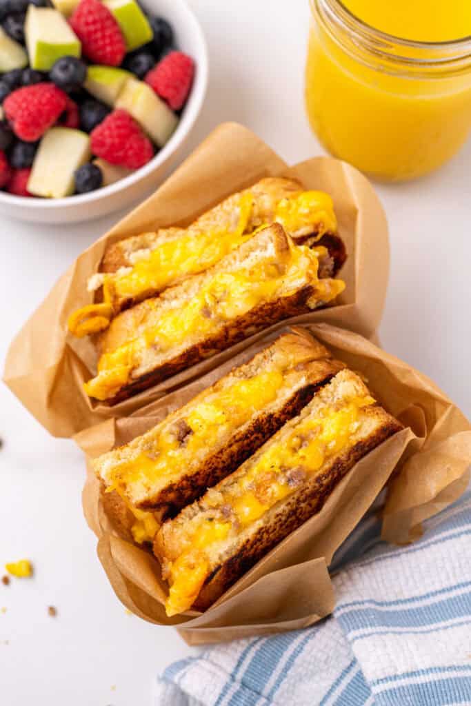 Grilled cheese breakfast sandwich with scrambled eggs and sausage served with fresh fruit and orange juice