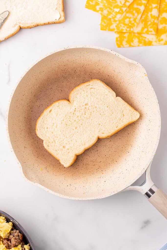 Buttered sourdough bread in a skillet for a Breakfast Grilled Cheese recipe on sourdough bread